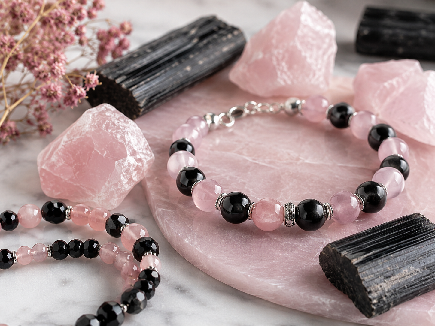 Bracelets, tourmalines noires et quartz roses bruts sur une plaque rose